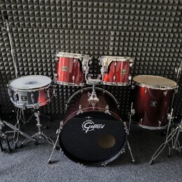 Vícedílná bicí souprava v tmavě červené barvě s chromovaným kováním. Na basovém bubnu je bílé logo Gretsch, stejné logo je viditelné i na ostatních b…