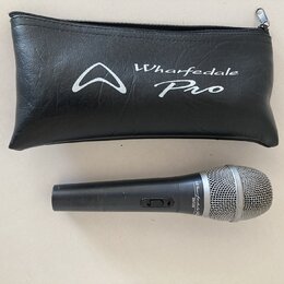 Černý dynamický mikrofon s kovovou síťkou v horní části. Na těle je nápis Wharfedale Pro DMS-10. Vedle mikrofonu je černý zipový pouzdro z umělé kůže…