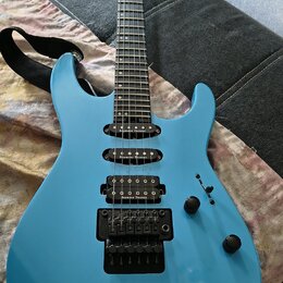Modře lakovaná elektrická kytara s černým hardwarem a třemi snímači. Na každém ze snímačů je bílý nápis Seymour Duncan. Na hlavě hmatníku je viditeln…