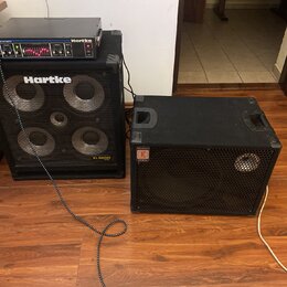 Na fotografii jsou dvě basové komba v černém provedení. Levý set tvoří zesilovač s nápisem Hartke a MODEL 400XL 400 WATTS umístěný na boxu s logem Ha…