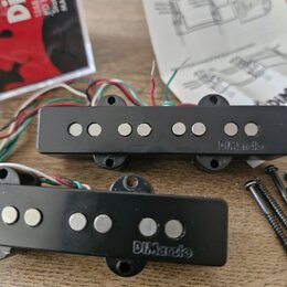 Dvě černé elektrické kytarové snímače značky DiMarzio. Oba mají plastový kryt s šesti viditelnými póly a připojovací kabely v různých barvách. Vedle…