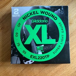 Krabice s dvěma sadami strun s nápisy NICKEL WOUND, D'Addario a XL. Na obalu je dále uveden model EXL220TP, označení SUPER LIGHT GAUGE a hodnoty 40,…