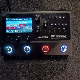 Černý kytarový procesor s displejem a ovládacími prvky. Na přístroji je bílý nápis VALETON GP-200LT MULTI-EFFECTS PROCESSOR. Displej zobrazuje text 0…