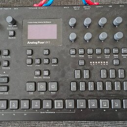Černý analogový tabletop syntetizér s nápisem Analog Four MKII. Přístroj obsahuje displej, množství tlačítek, posuvníky a otočné knoflíky. V pravém h…