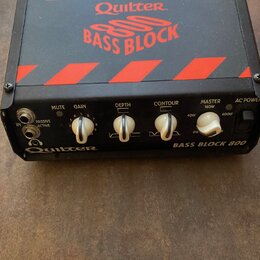 Černý basový zesilovač s červenými šikmými pruhy na horní straně. Na vrchu je nápis Quilter BASS BLOCK 800 a na předním panelu vpravo text BASS BLOCK…