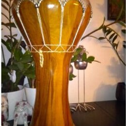 Dřevěný buben typu djembe s hnědým povrchem a viditelnou strukturou dřeva. Horní obruč je potažena světlým materiálem s ozdobným vzorem a k tělu je p…