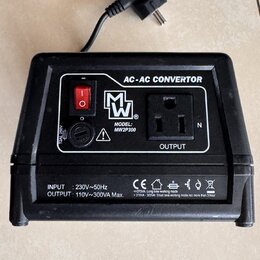 Černý AC-AC CONVERTOR s napájecím kabelem a zástrčkou. Na přední straně je červený vypínač, pojistka T2AL 250V a výstupní zásuvka OUTPUT. Je zde logo…