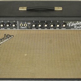 Kytarový zesilovač v černém krytu s béžovou textilní mřížkou. Na ovládacím panelu jsou nápisy Vibrolux Reverb Amp, FENDER MUSICAL INSTRUMENTS a DESIG…
