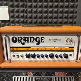 Kytarový zesilovač v oranžovém vinylu s bílým předním panelem. Na panelu je velký nápis ORANGE a modelové označení ROCKERVERB 50. Zesilovač má ovláda…