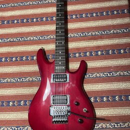Elektrokytara s červeným lakovaným tělem a hnědým hnedým hmatníkem. Na hlavě je bílé logo Ibanez a na krku nápis RG 5220. Kytara má dva humbuckery, t…