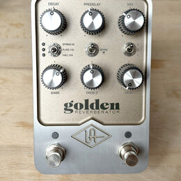 Kytarový efekt v kovovém šasi s nápisem golden REVERBERATOR a logem UA. Zařízení má šest ovládacích knoflíků s popisky DECAY, PREDELAY, MIX, BASS, TR…