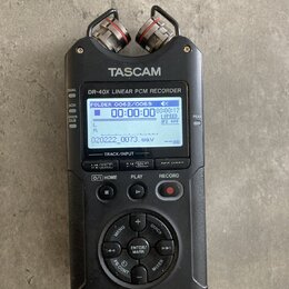 Černý digitální nahrávač s nápisy TASCAM a DR-40X Linear PCM RECORDER. Zařízení má LCD displej s zobrazením času a vlnové formy, horní mikrofony a ov…
