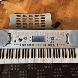 Stříbrný digitální klavír značky MEDELI, model mc70. Nástroj má vestavěné reproduktory po obou stranách a ovládací panel s displejem a tlačítky. Souč…