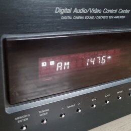 Černý Digital Audio/Video Control Center s nápisem DIGITAL CINEMA SOUND / DISCRETE 5CH AMPLIFIER. V displeji svítí červeným text AM 1476. Pod displej…