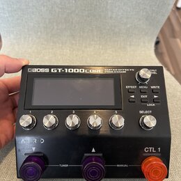 Černý kytarový procesor s nápisem BOSS GT-1000CORE GUITAR EFFECTS PROCESSOR. Zařízení má centrální displej, pět očíslovaných otočných ovladačů (1–5),…