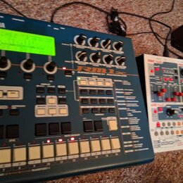 Modrý sekvenční modul s nápisy YAMAHA a RM1x SEQUENCE RECORDER MIXER. Zařízení má zelený podsvícený displej, několik otočných knoflíků a bílé orazvác…