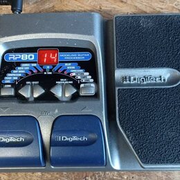 Šedý kytarový procesor Digitech RP80 Modeling Guitar Processor s integrovaným expresním pedálem. Zařízení má digitální displej zobrazující červenou č…