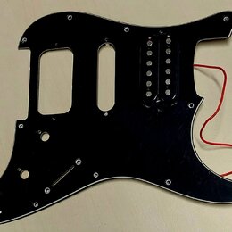 Černý plastový pickguard pro elektrickou kytaru s jedním instalovaným humbuckerem. Z povrchu jsou viditelné drobné škrábance a stopy používání, z nás…