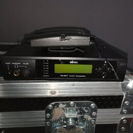 Černý přístroj s nápisem MIPRO a označením M1-808T Stereo Transmitter. Na přední straně jsou umístěny zelený LCD displej, ovládací prvky a konektor p…