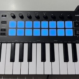 Černý kompaktní MIDI kontrolér s klaviaturou a názvem LAUNCHKEY MINI. Horní panel obsahuje 8 modrých podsvícených čtvercových políček, několik otočný…