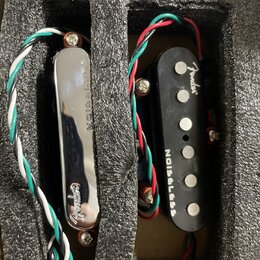 Dvě kytarové snímače umístěné v černé pěnové výplni. Levý snímač má chromovaný kryt s nápisy NOISELESS a Fender. Pravý snímač je černý, má šest vidit…