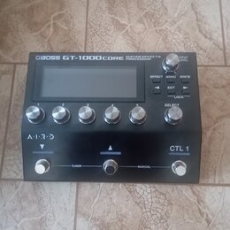 Černý kytarový procesor s nápisem BOSS GT-1000CORE GUITAR EFFECTS PROCESSOR. Zařízení má displej, pět ovládacích knoflíků s čísly 1 až 5, tlačítka EF…