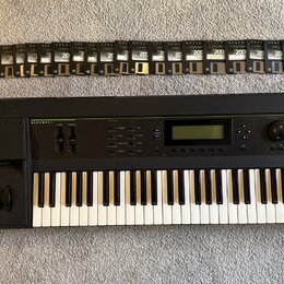 Černý klavír s nápisy KURZWEIL a K2000 V2. Vedle nástroje je položen manuál s názvem K2000 MUSICIAN'S GUIDE a KURZWEIL, spolu s elektronickou deskou.…