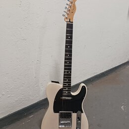 Elektrická kytara s bílým tělem, černým pickguardem a hnědým hmatníkem. Na hlavě je viditelné logo Fender. Nástroj má jeden humbucker v pozici mostu…