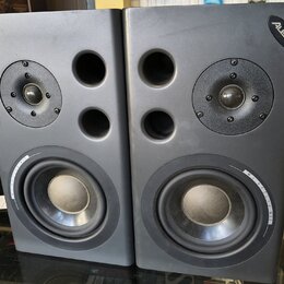 Dva šedé studiové reproduktory značky Alesis. Každý obsahuje jeden výškovej reproduktor, dva bassreflexní otvory a jeden basový reproduktor s nápisem…