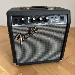 Kytarový kombo zesilovač s černým povrchem a stříbrnou textilní mřížkou. Na ovládacím panelu jsou nápisy INPUT, GAIN, VOLUME, TREBLE, BASS a POWER, p…