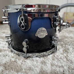 Modrý buben s kovovými obručmi a ladicími šrouby. Na korpusu je nalepený oválný štítek s nápisy „Carl Palmer“, „PLATINUM SERIES“ a „All-Maple Shell“.…
