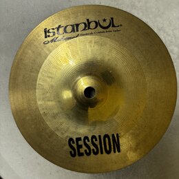 Zlatavý kovový činel s nápisem istanbul® a pod ním menším písmem Mahmet Handmade Cymbals from Turkey. Ve spodní části je uveden model SESSION. Činel…