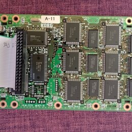 Zelená tiskovaná deska s osazenými integrovanými obvody a elektronickými součástkami. V horní části je bílá nálepka s nápisem A-11 a pod ní logo KORG…