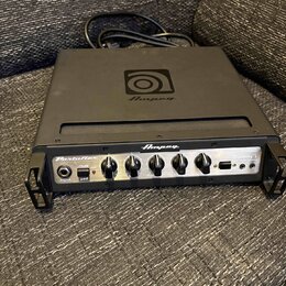 Černý basový zesilovač značky Ampeg s nápisem PortaFlex. Na horní straně je umístěno logo Ampeg. Přední panel obsahuje ovládací knofíky, přepínač -15…