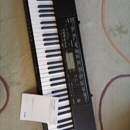 Černý digitální klavír s bílými a černými klávesami. Na ovládacím panelu je nápis CTK-3500 a logo CASIO. K nástroji přikládaný papírový dokument nese…
