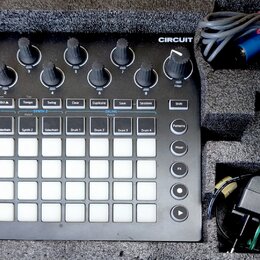 Černý sekvenční syntetizátor Novation CIRCUIT v dopravním pouzdře z pěnového materiálu. Zařízení má bílé podsvícené pady, několik otočných potenciome…