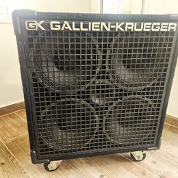 Černý basový reproduktor s kovovou mřížkou, za kterou jsou vidět čtyři velké membrány. V horní části je bílý nápis GALLIEN-KRUEGER a logo GK. Box sto…