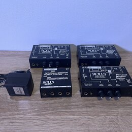 Na fotografii jsou čtyři černé kovové boxy s ovládacími prvky a konektory. Tři z nich mají nápisy ROLL'S MADE IN USA, www.rolls.com a Personal Monito…