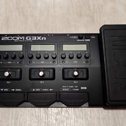 Černý kytarový efektový procesor s nápisem ZOOM G3Xn Multi-Effects Processor. Zařízení má tři LCD displeje, několik ovládacích knoflíků a tři spodní…