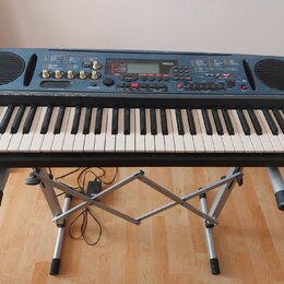 Tmavě modrý digitální klavír značky YAMAHA s modelem DTX. Nástroj je umístěn na stříbrném X-kovém stojanu. Na ovládacím panelu jsou viditelné knofíky…