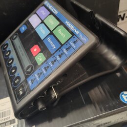 Černý procesor vokalových efektů s dotykovým displejem a ovládacími prvky. Na horní části je nápis TC HELICON a model VOICELIVE Touch. Displej obsahu…