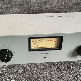 Bílý rackový kompresor s nápisy TUBE COMPRESSOR/LIMITER 1000 a ANTHONY DEMARIA LABS. Na předním panelu se nachází VU metr s označením ADL 1000, dva č…