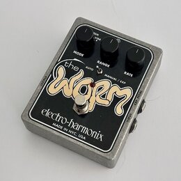Kytarový efekt v kovovém šedém šasi s černým čelem. Na čele je bílý nápis the WORM a značka electro-harmonix s doplňkem MADE IN NYC, USA. Efekt má tř…