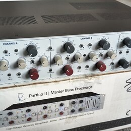 Stříbrný rackový procesor s černým horním krytem, umístěný na kartónovém balení. Na předním panelu je nápis PORTICO II Master Buss Processor a v prav…