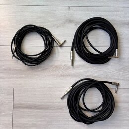 Tři černé audio kabely s kovovými konektory typu jack. Kabely jsou svinuté do klubíčků a položené na světlém laminátovém povrchu. Na konektorech nejs…