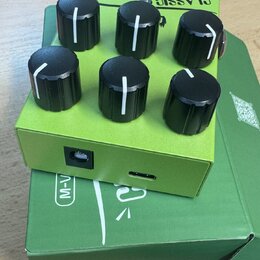Zelený kytarový efekt s šesti černými oválnými knoflíky. Na horní straně je nápis CLASSIC DELAY a grafický symbol vlnovky. Efekt leží na zelené krabi…
