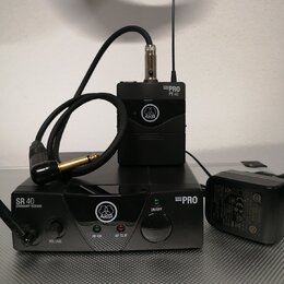 Černý bezdrátový mikrofonní systém značky AKG. Na přijímači je nápis SR 40 STATIONARY RECEIVER a MINI PRO, na vysílači MINI PRO PT 40. Soubor obsahuj…