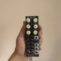 Černý kompaktní stereo mixér s bílými ovládacími knoflíky. Na horní části je nápis STEREO MIXER+ a pod ním AUDAC810. Zařízení obsahuje čtyři knoflíky…