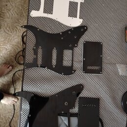 Na fotografii jsou třipickguardy pro elektrickou kytaru a dvě doprovodné krytky. Horní pickguard je bílý, prostřední a spodní jsou černého provedení.…