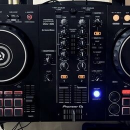 Černý DJ controller s dvěma jogovými koly a centrálním míchacím panelem. Na horní části je nápis PERFORMANCE CONTROLLER DDJ-400 a logo rekordbox, v d…